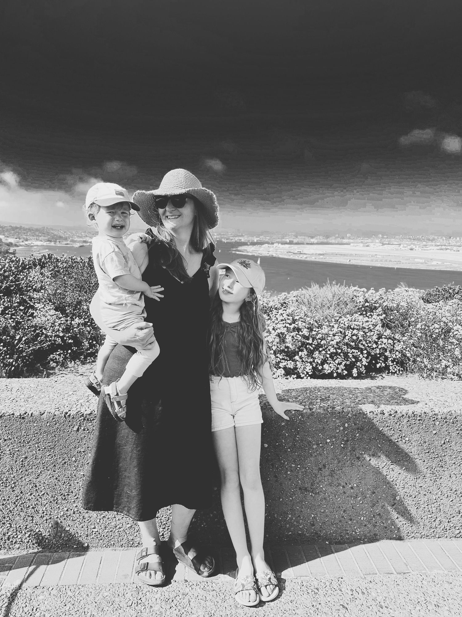 Family enjoying ocean view together on coastal path in black and white.