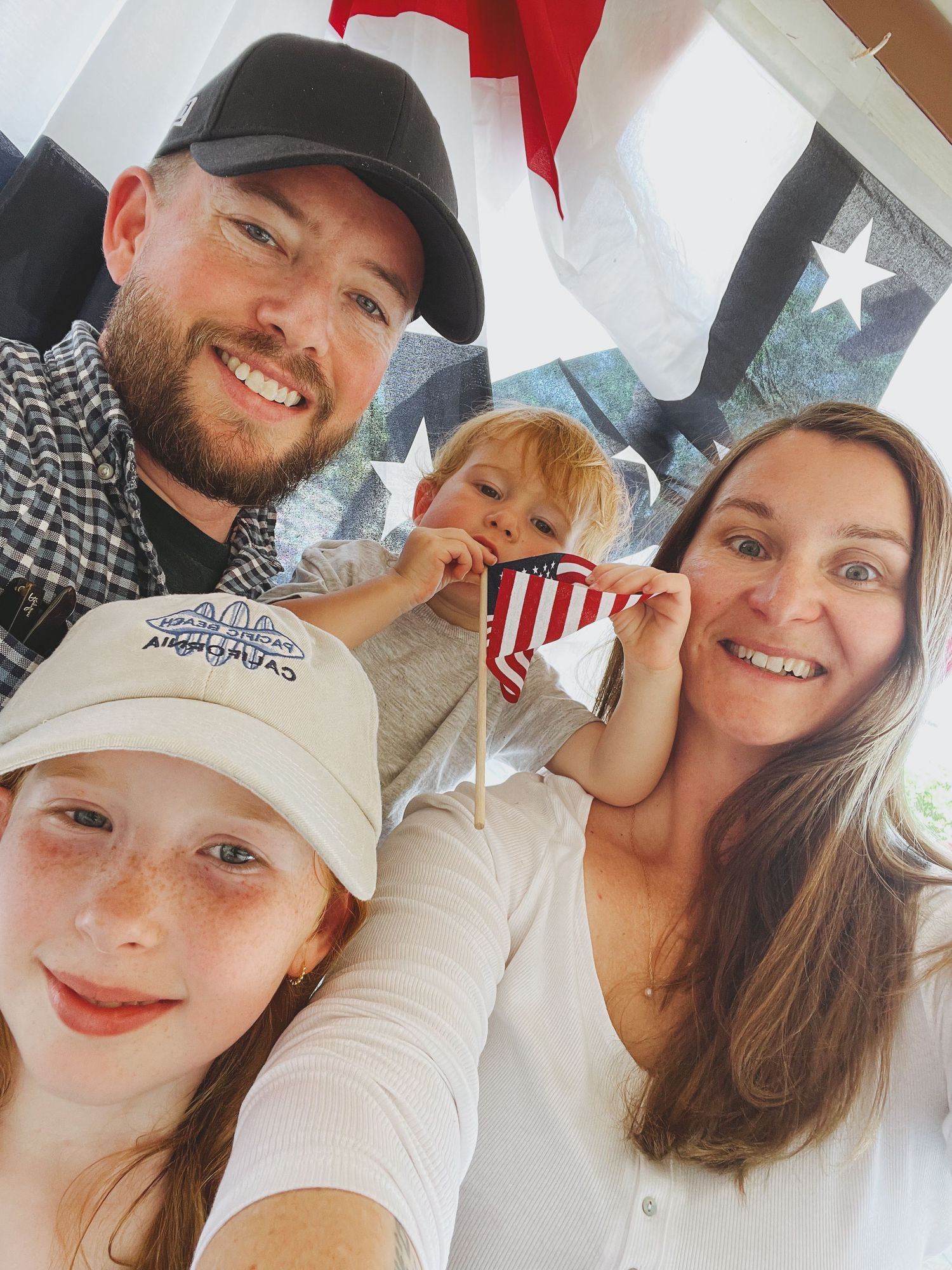 Family takes selfie together with American flag in background.