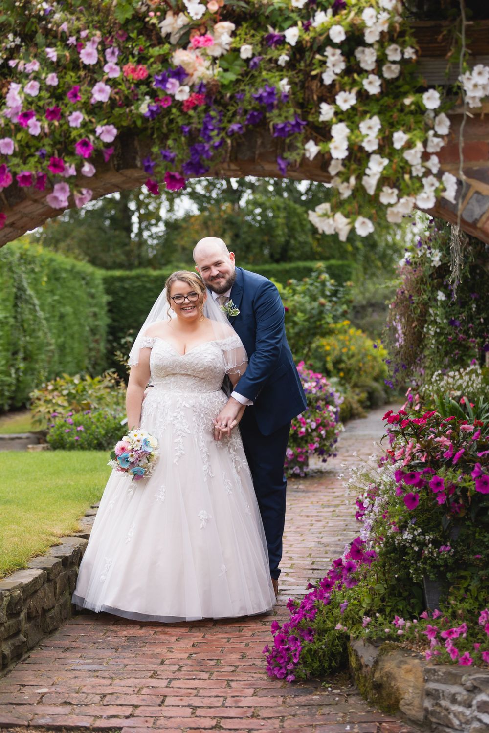 Wedding couple under flower archway Random Hall Hotel