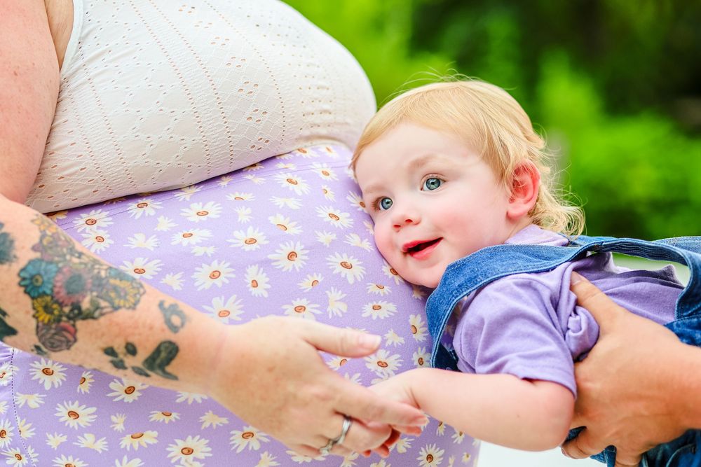 A close up image of a baby boy hugging his mothers pregnant belly.