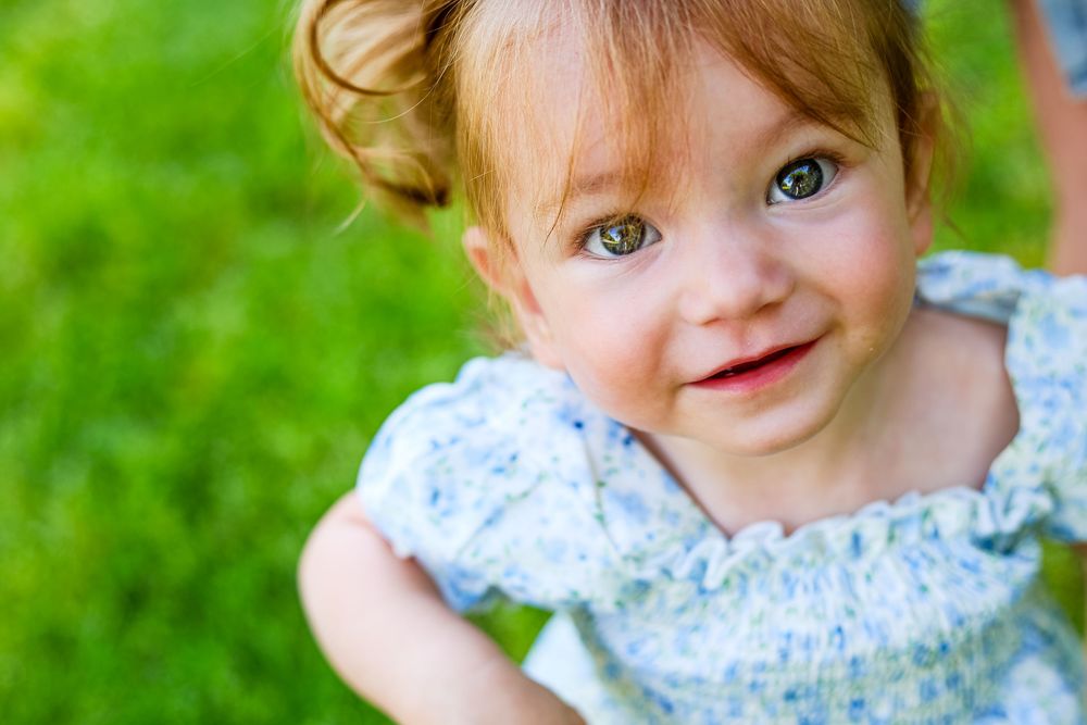 A candid image of a baby girl looking up at the camera.