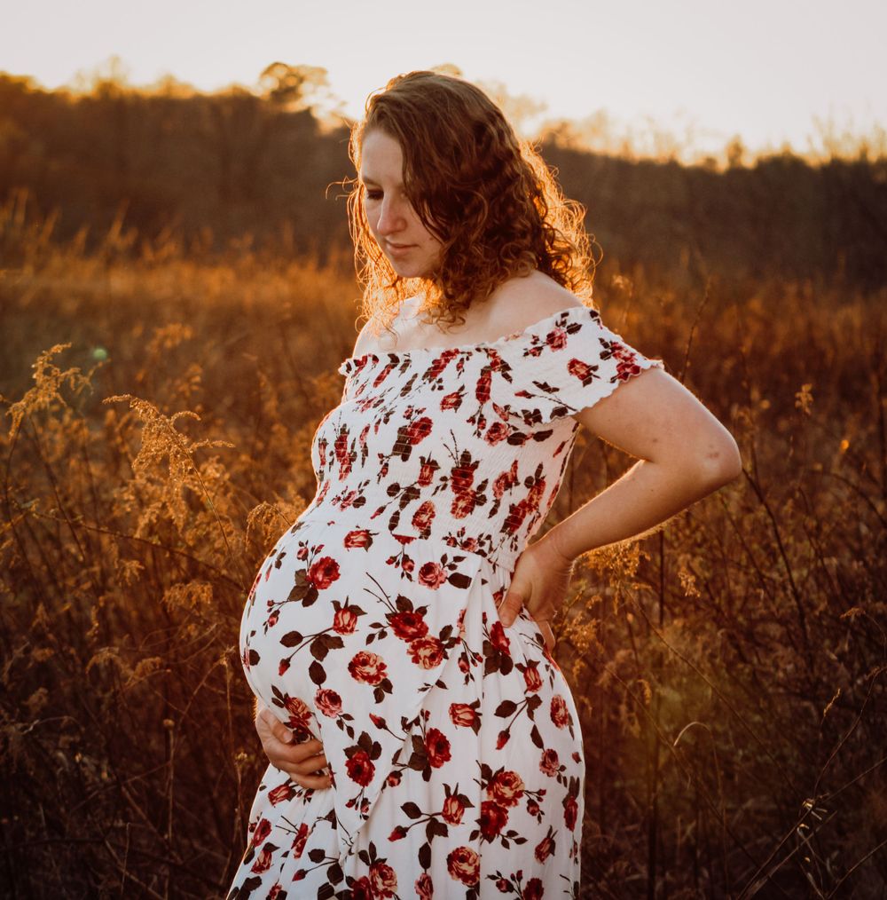 Maternity picture taken at Seven Islands State Birding Park during sunset - Golden Hour of a woman with a hand resting on her hip and belly.