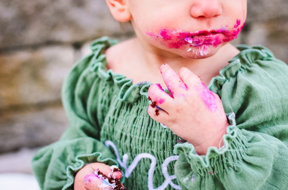 A close-up image of a one-year old baby's cake smash session. Hands and mouth picture.