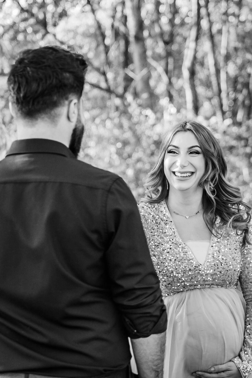 A candid maternity image of a mother and father facing each other, with her holding her belly (Black & white)