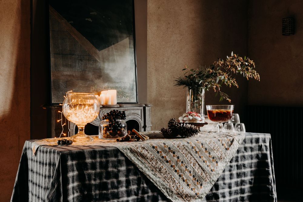 Elegant table display with glowing centerpiece, decorative vases, and patterned tablecloth in a moody, dimly lit setting.