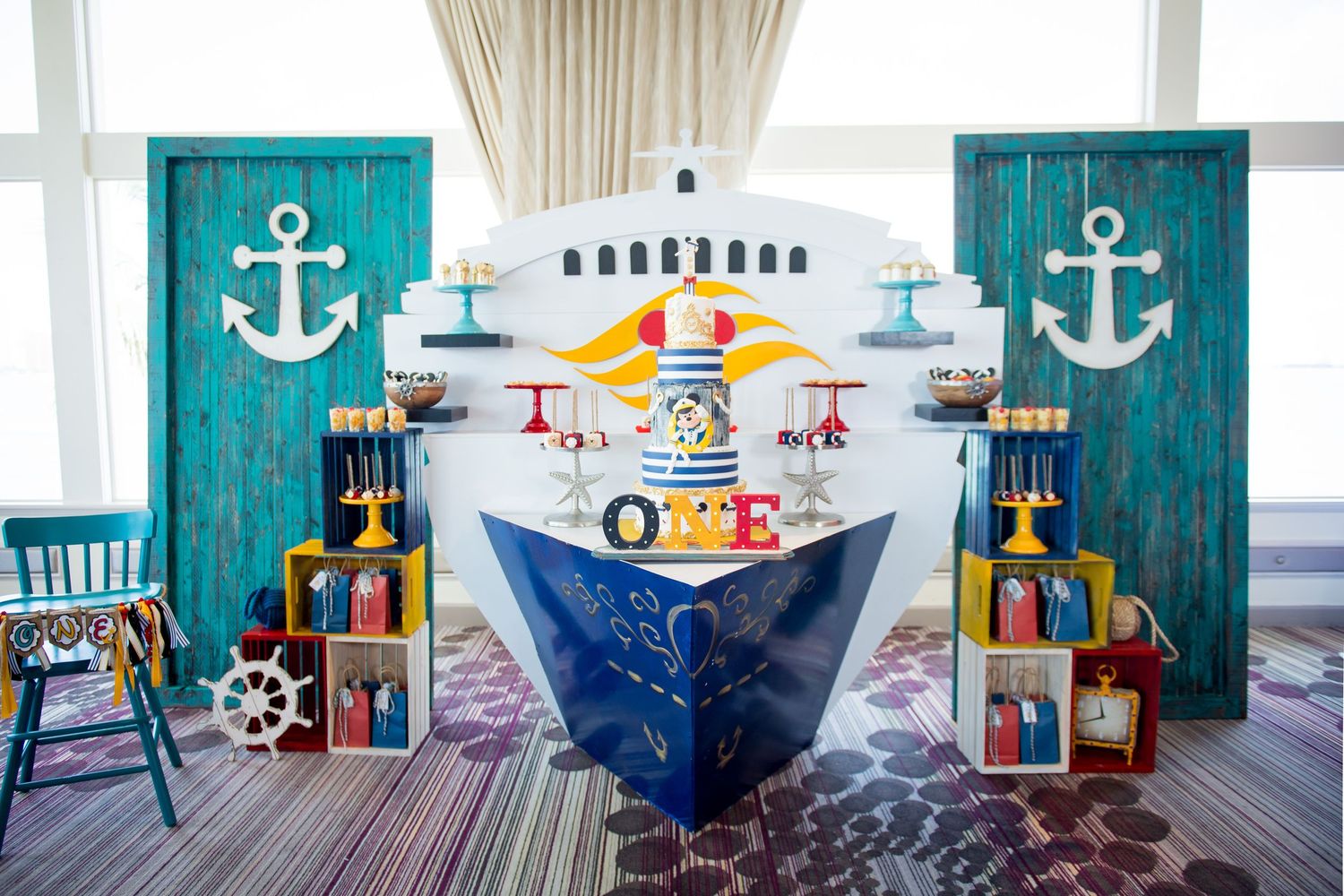 Nautical themed party decoration with blue ship backdrop, anchor banners, and maritime props for a celebration setup.