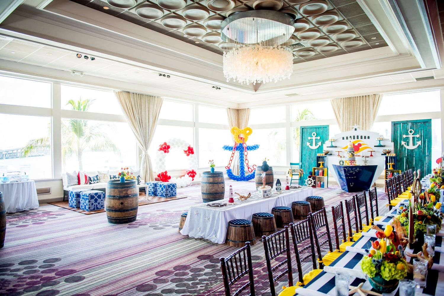 Nautical themed party room with anchor decorations, life preservers, crystal chandelier and elegant dining setup.