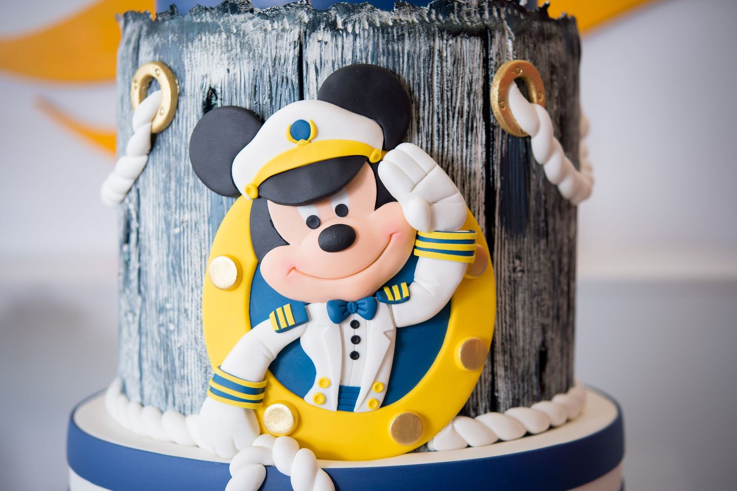 A nautical themed cake decorated with Mickey Mouse wearing a sailor uniform and yellow life preserver details.