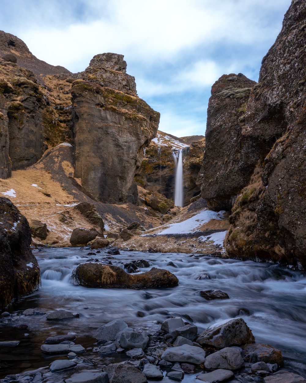 Kvernufoss - a waterfall at the end of a long rocky gorge falls dramatically into a pool that becomes a stream.