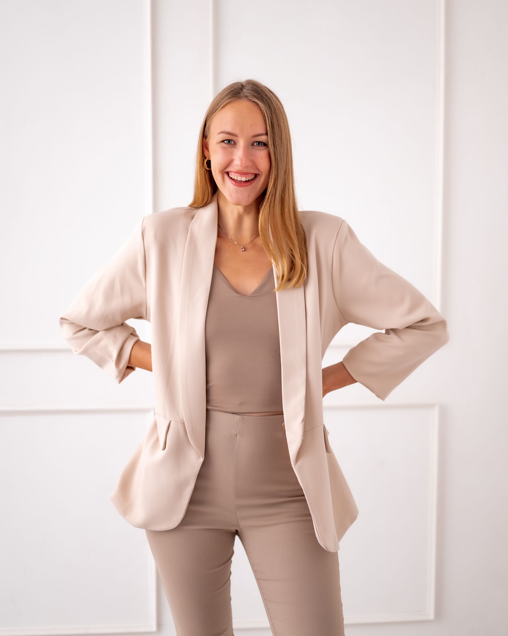 Energetic pose in neutral-toned business suit against white background.