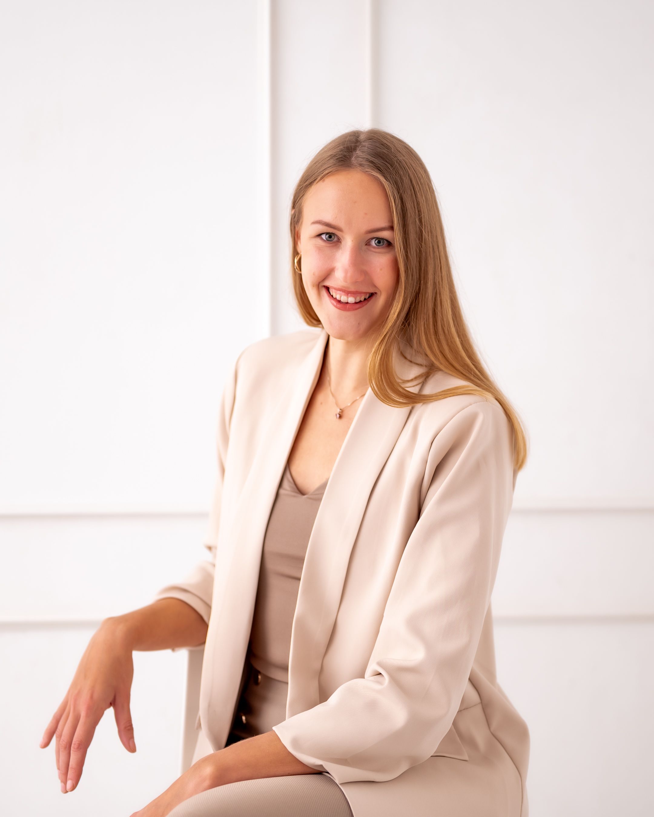 Elegant professional headshot with warm smile wearing neutral-toned business attire.