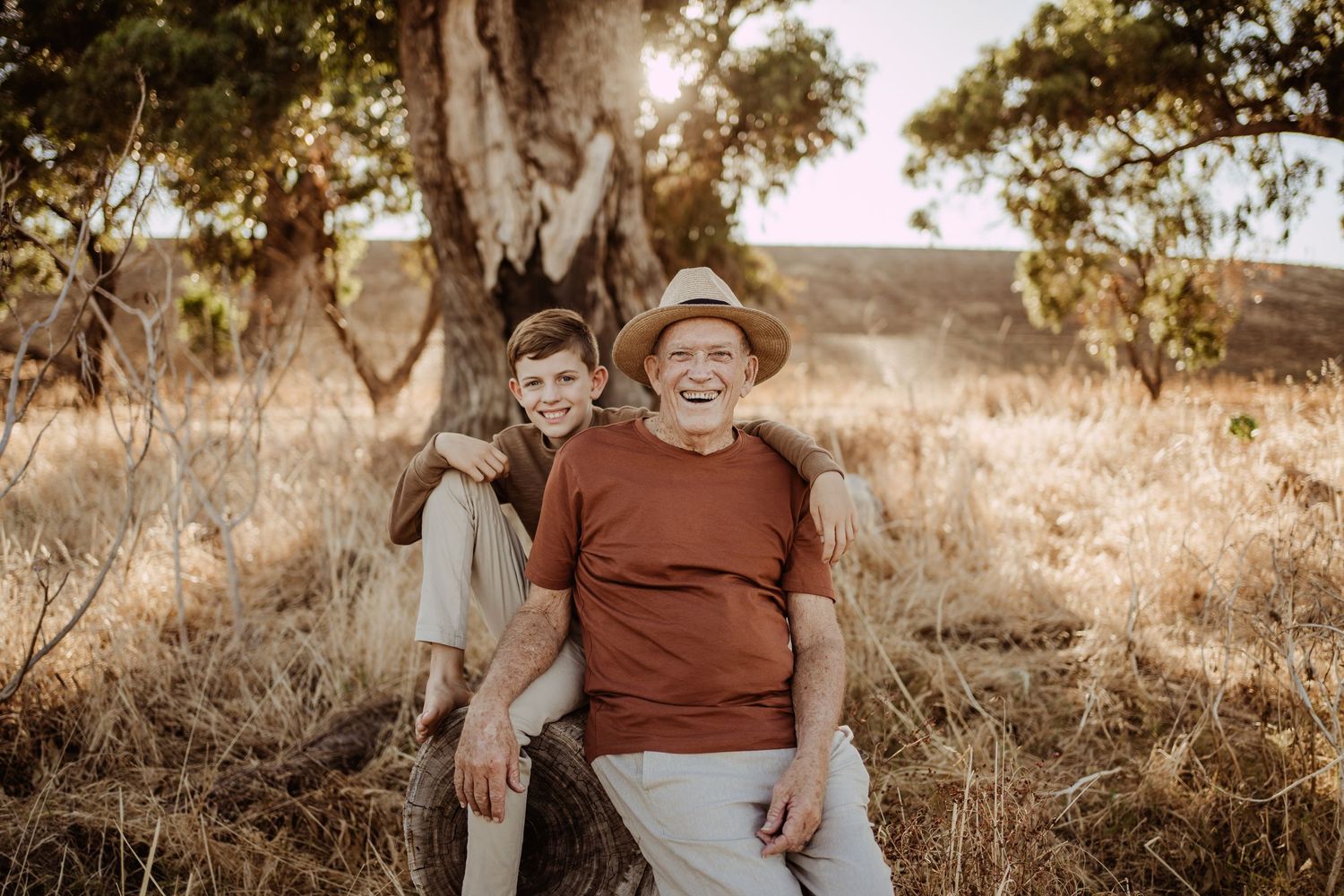 Two people share a warm moment while sitting together on a hill during sunset.