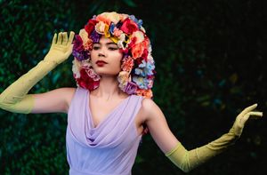 Creative editorial portrait of High Fashion model Sydney  wearing a colorful floral headpiece and artistic styling during a beauty shoot
