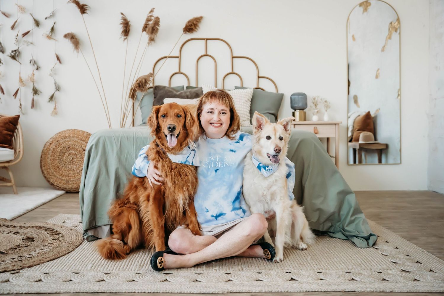 Two friendly dogs pose with their companion on a cozy living room floor with boho decor.