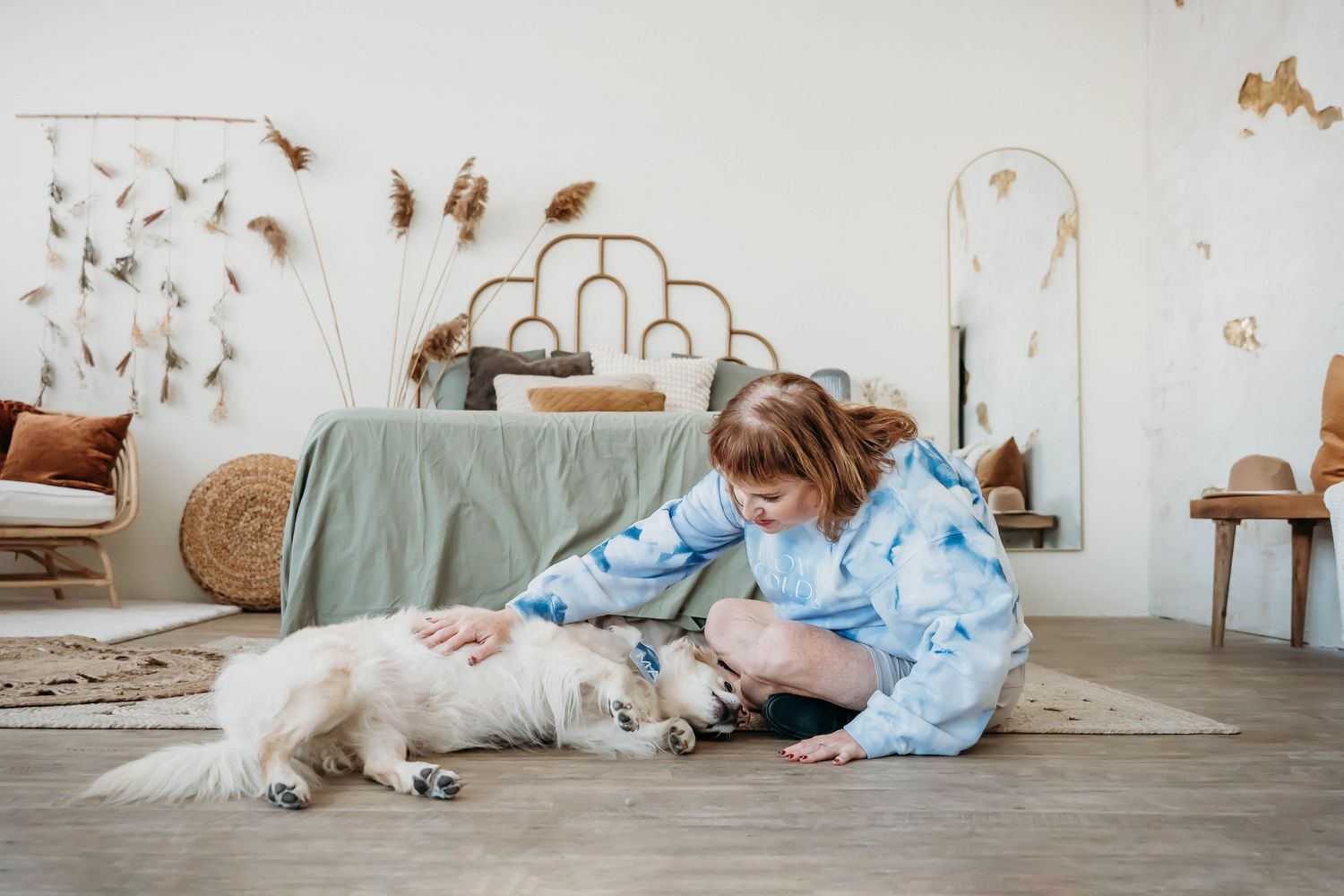 Gentle interaction between dogs and their companion on hardwood floor in a cozy living space.