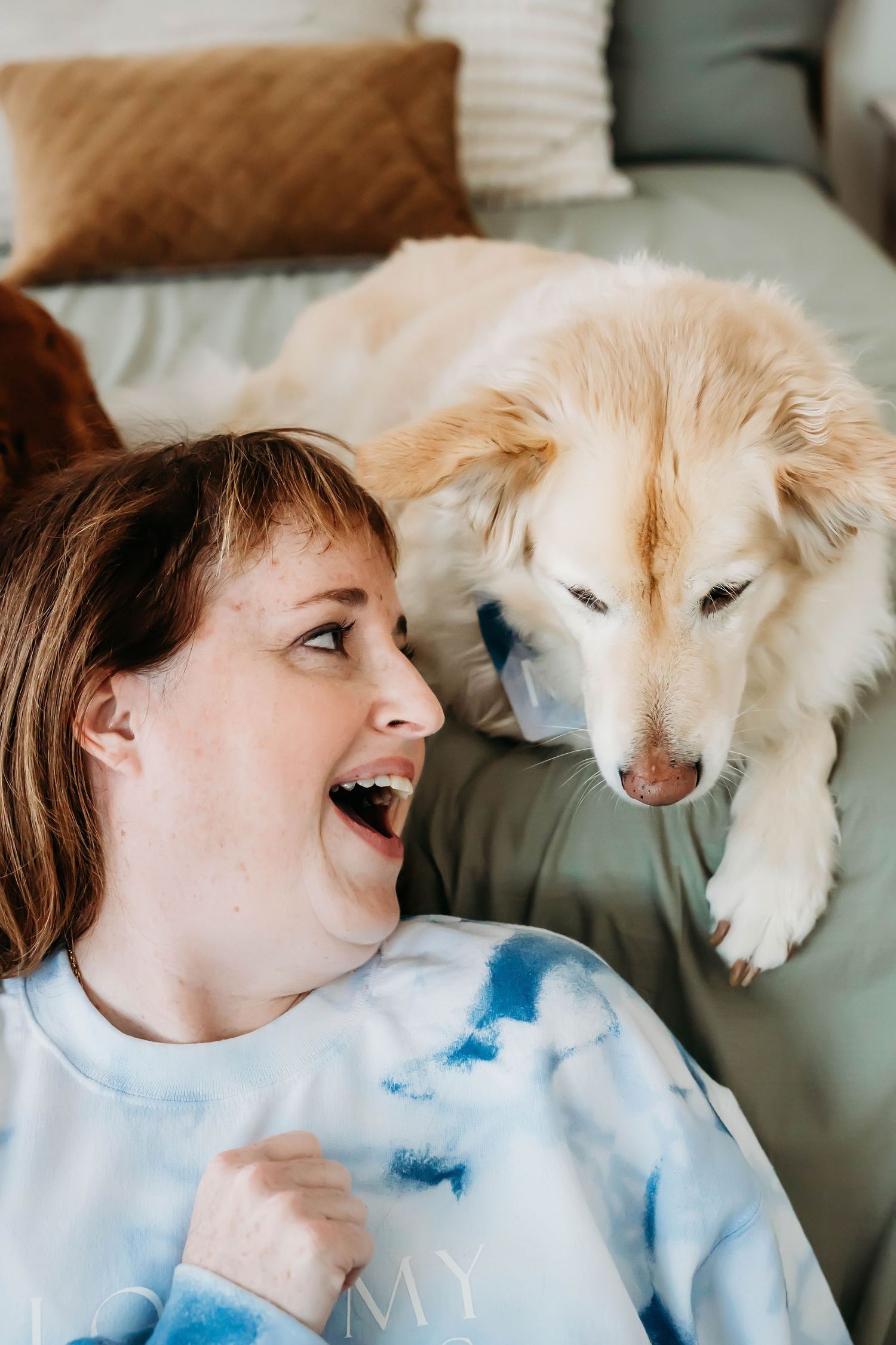 Joyful interaction between cream-colored dog and companion on a comfortable green couch.
