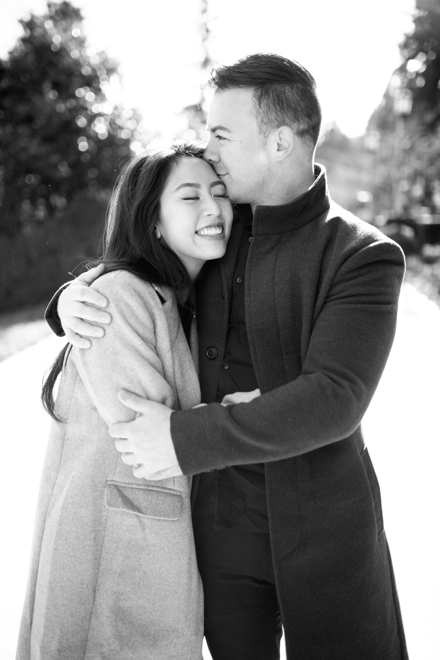 Intimate black and white portrait of a couple embracing in winter coats.