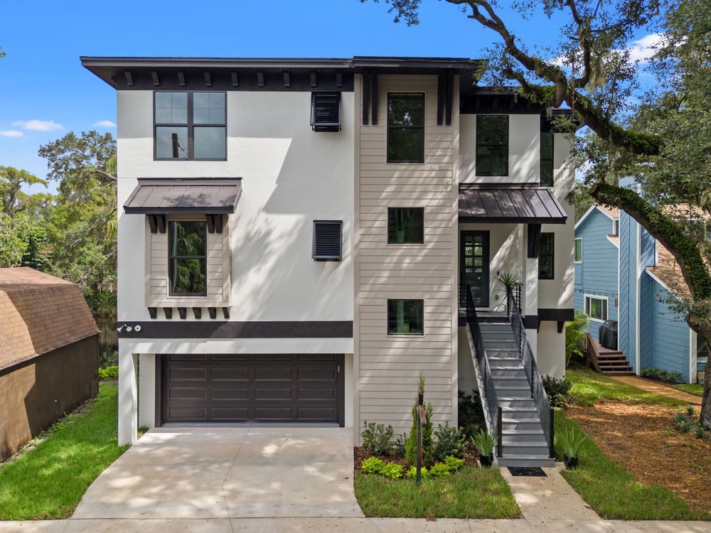 Contemporary house exterior with gray siding and black accents shown in daylight.