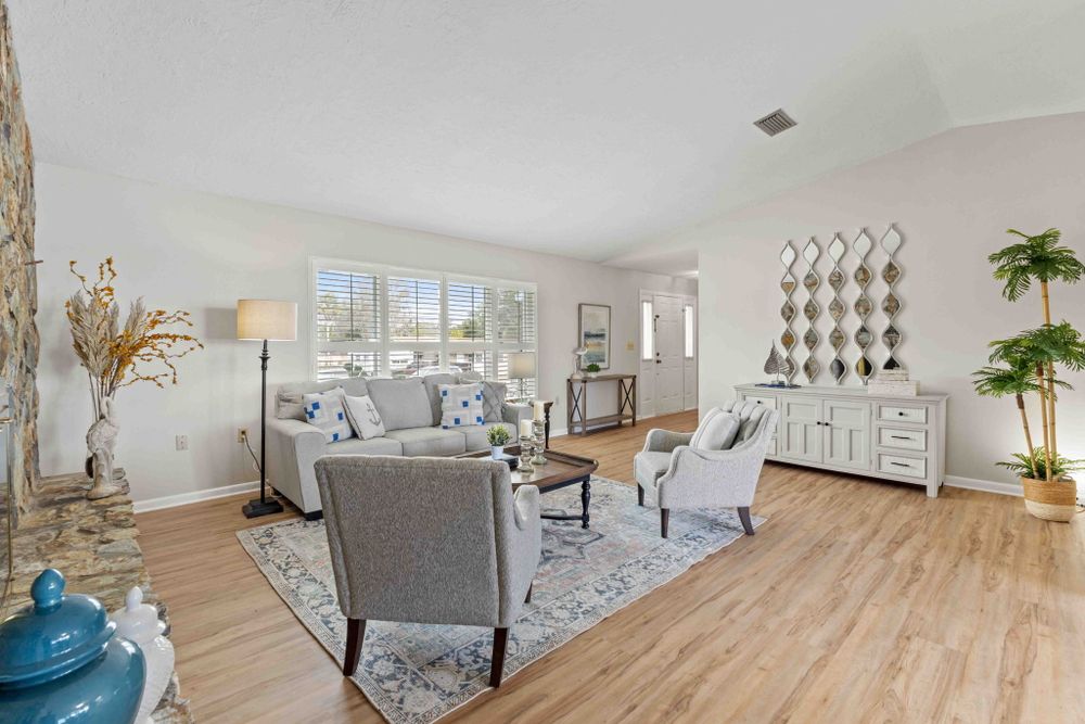 Open concept living space with coastal decor, comfortable seating, and large windows.
