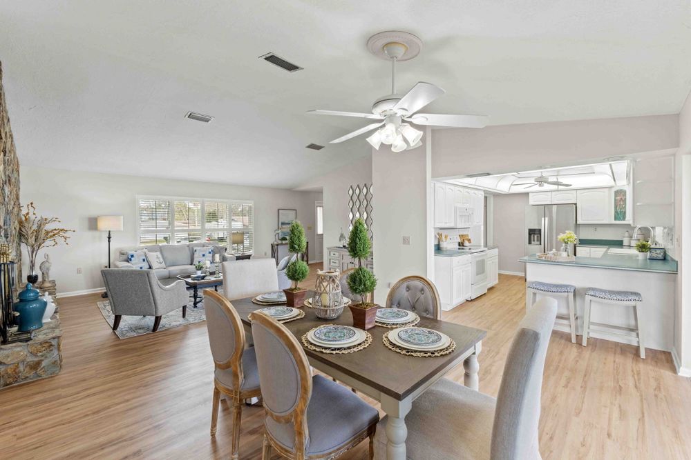 Bright open concept living and dining area with ceiling fan and coastal decor.