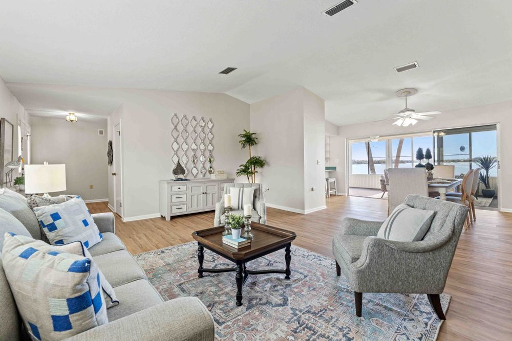 Modern living room with white furniture, blue accents, and hardwood floors in an open concept space.