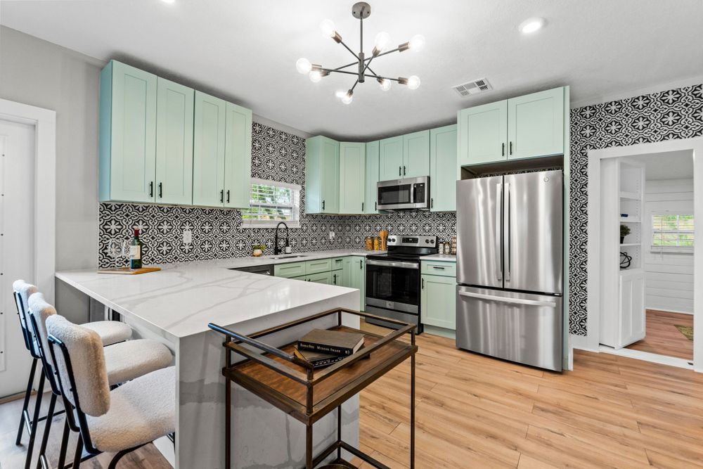 Contemporary kitchen featuring mint cabinets, stainless appliances and geometric backsplash.