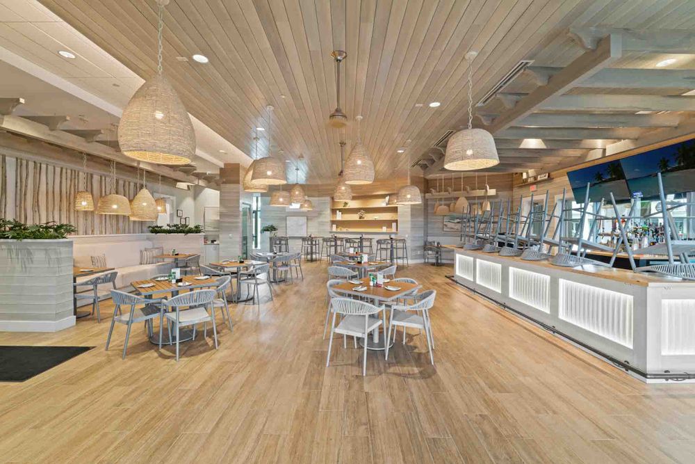 Spacious dining area with wood-paneled ceiling and modern pendant lighting.