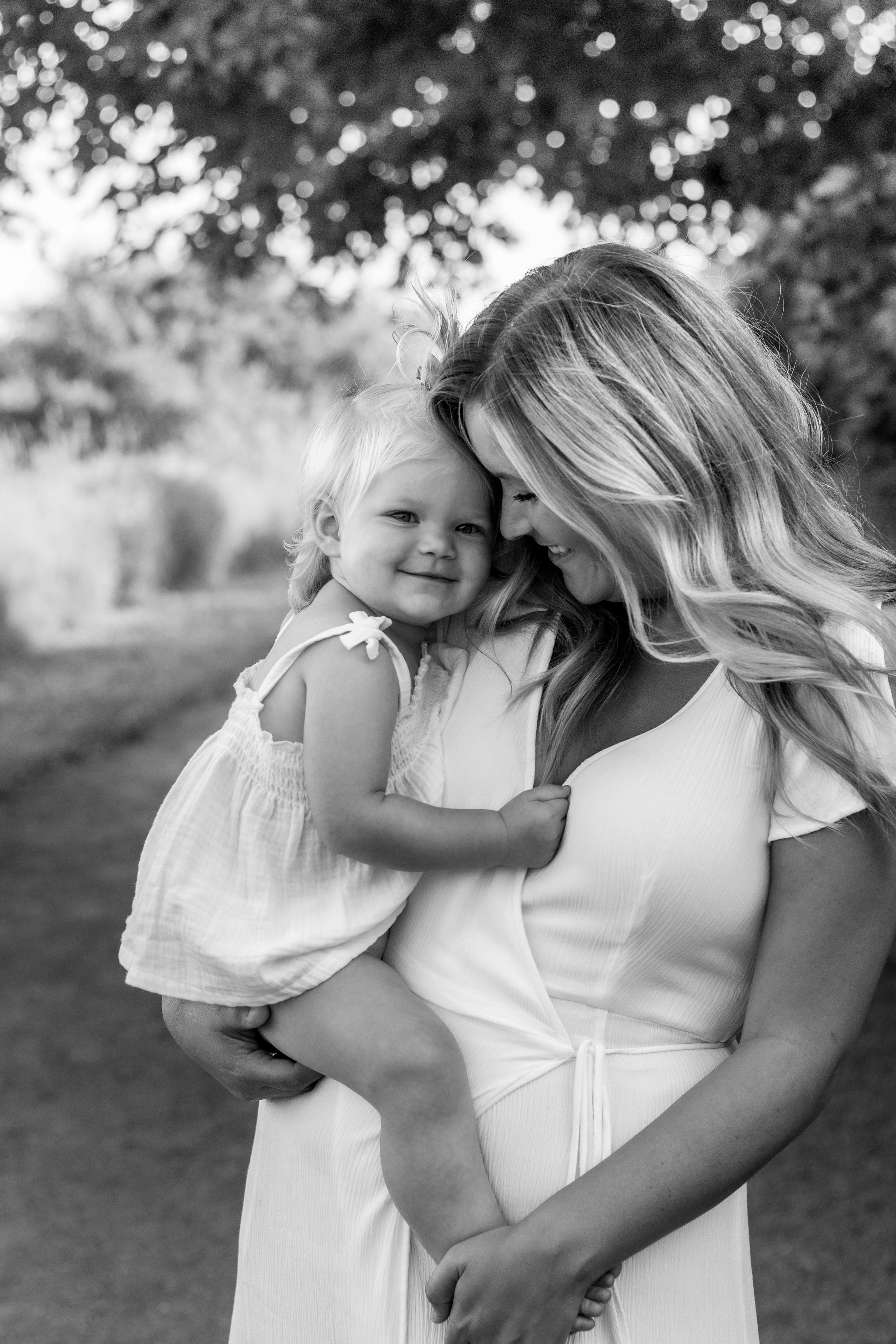 Black and white portrait of tender moment between parent and child outdoors.