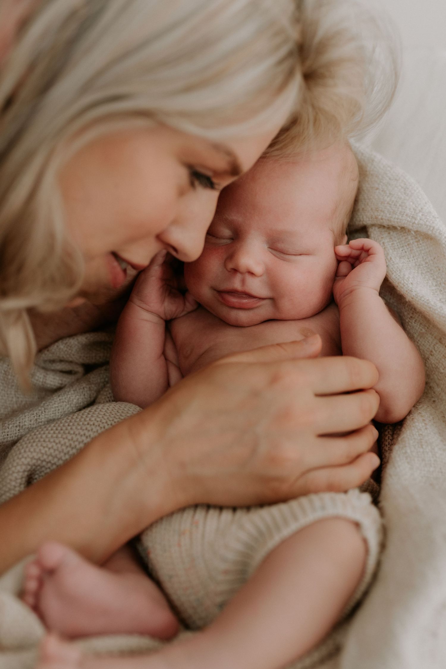 Sweet nurturing moments captured in soft natural light on white bedding.
