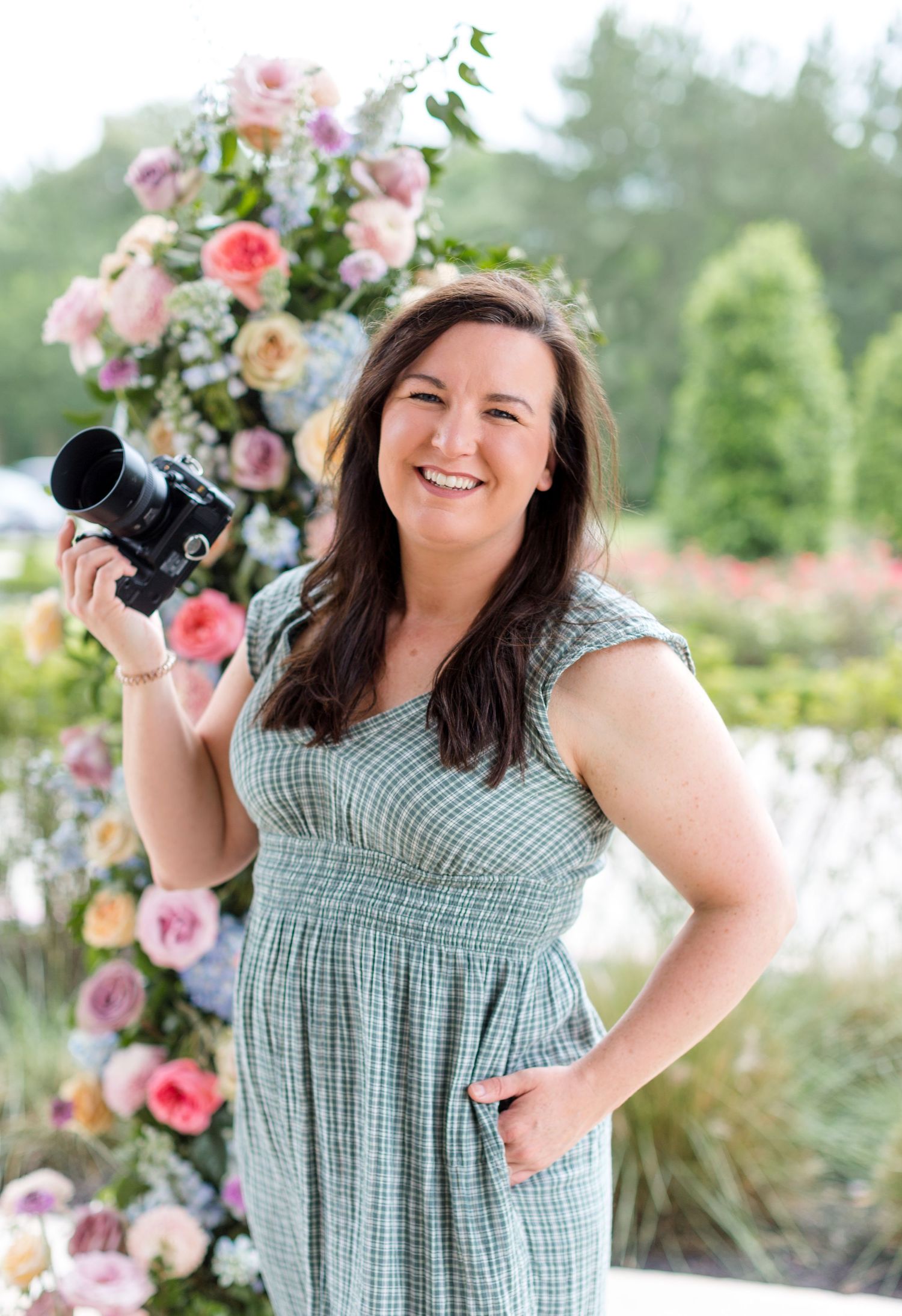 Central Illinois photographer Julie Loy Photography holding a camera in front of a flower arch