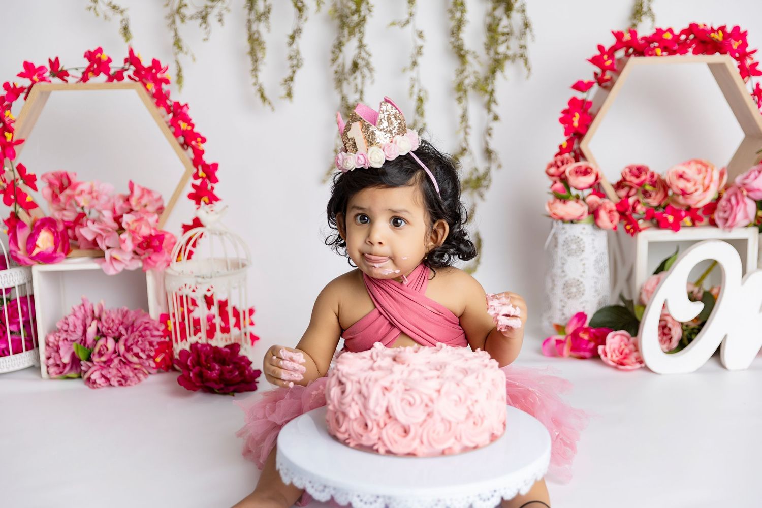 Cake smash photography setup with pink decorations and floral arches.
