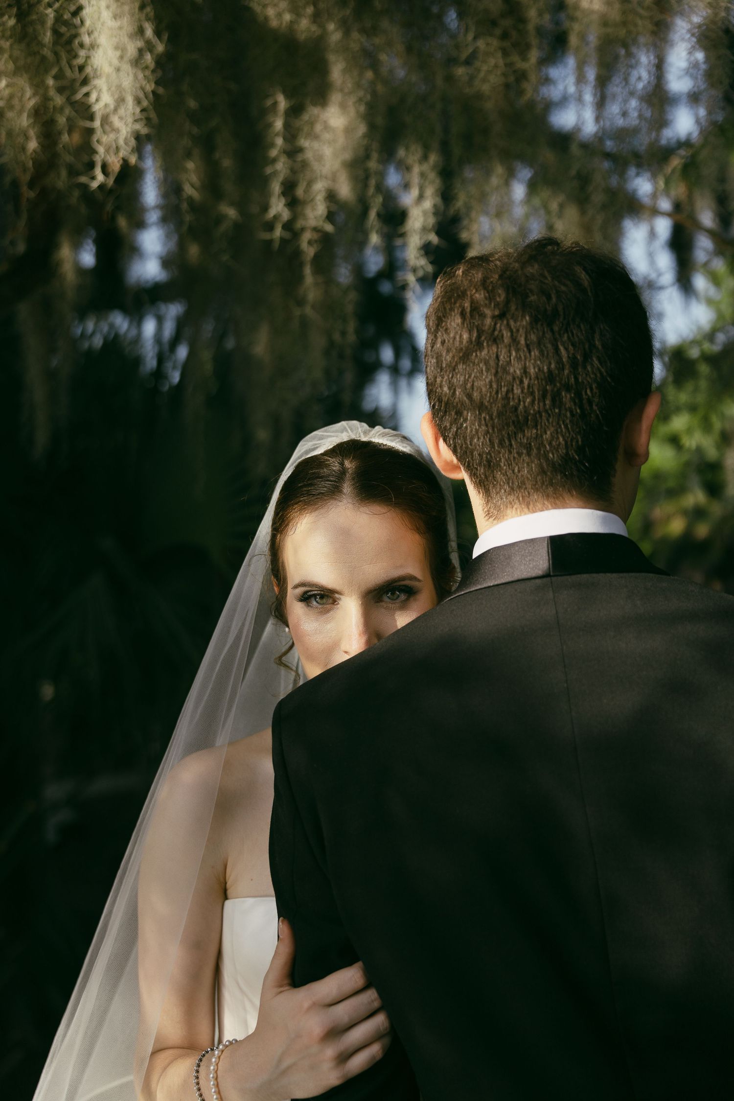 A couple shares a romantic moment together outdoors on a misty day with mature oak trees in the background.