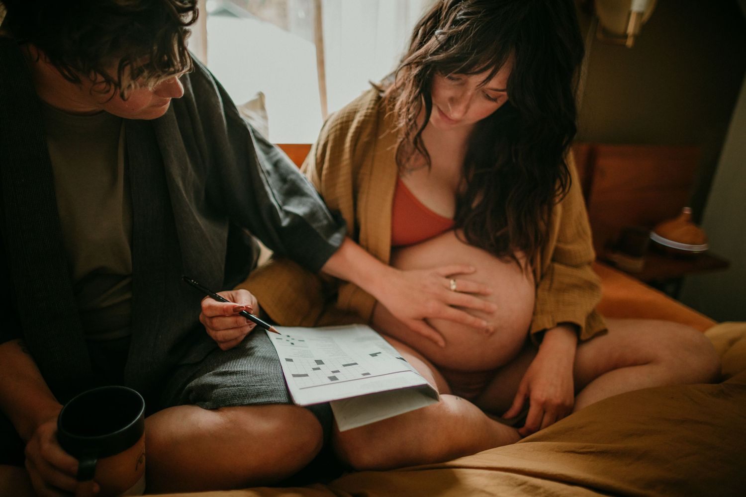queer couple does a crossword puzzle in bed in-home documentary photography session portland oregon rushes & waves