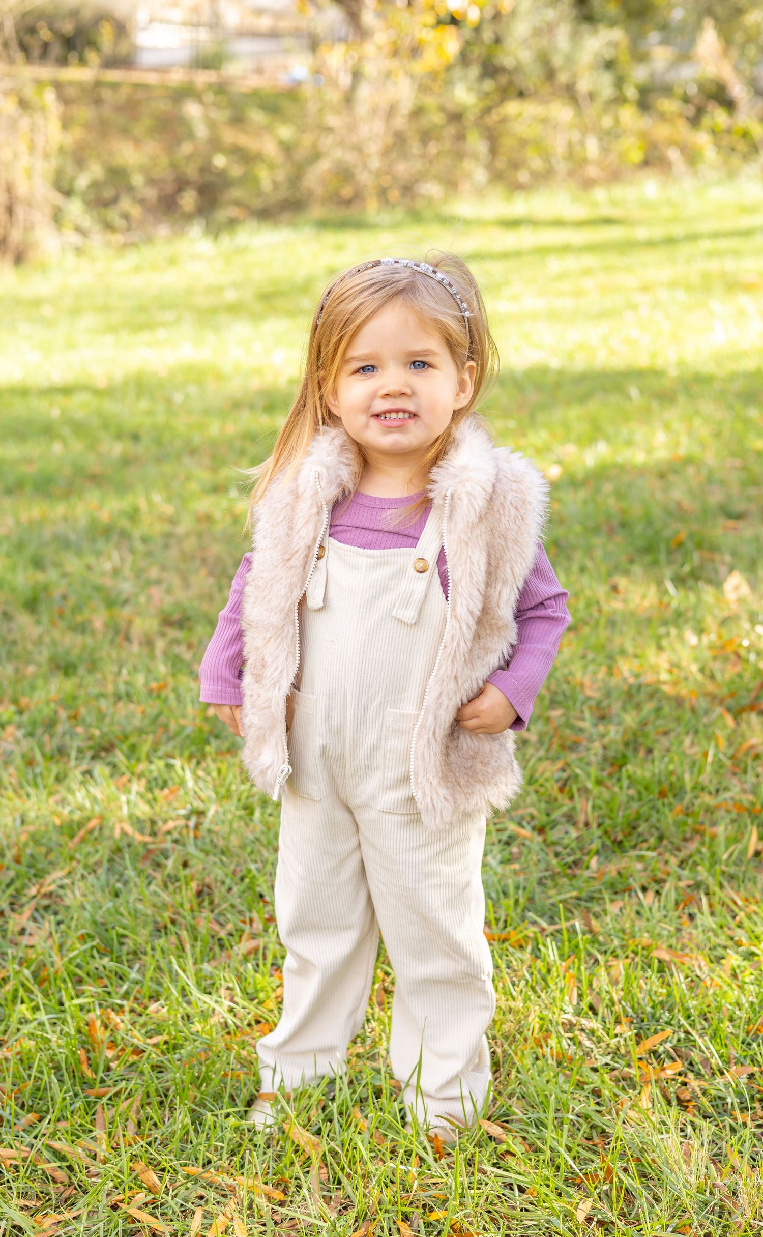 Little girl smiling and standing in a beautiful field.