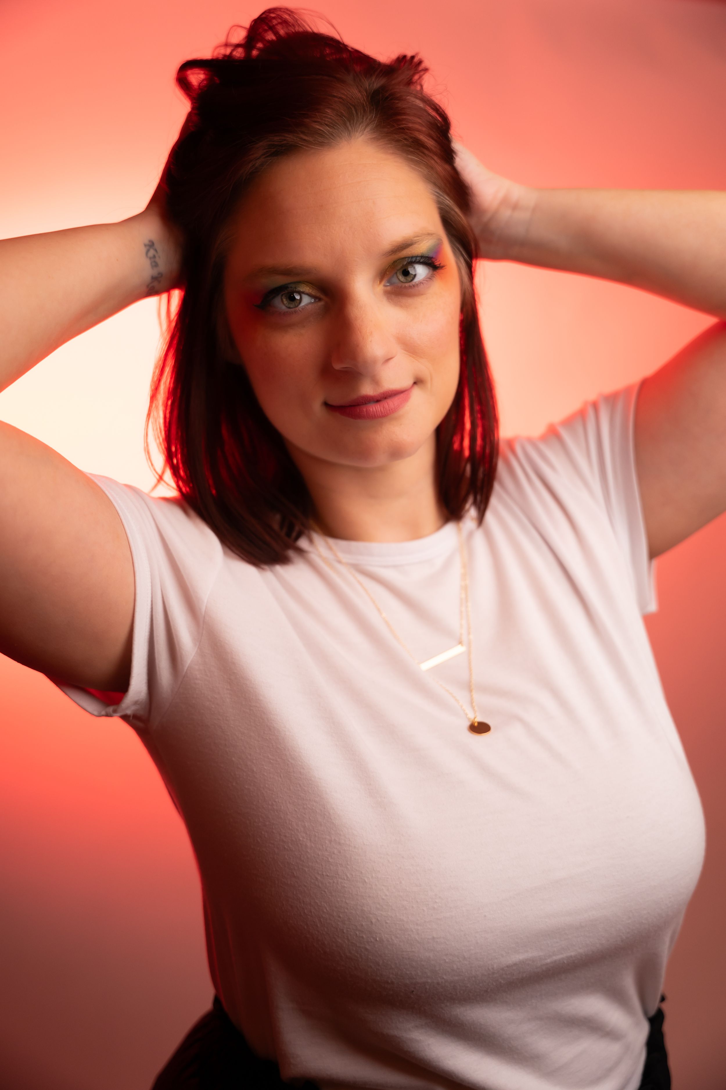 Casual portraits in a white t-shirt against a reddish-pink background.