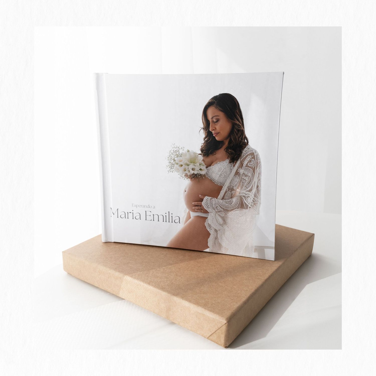 Professional maternity album displayed on wooden stand against white background.