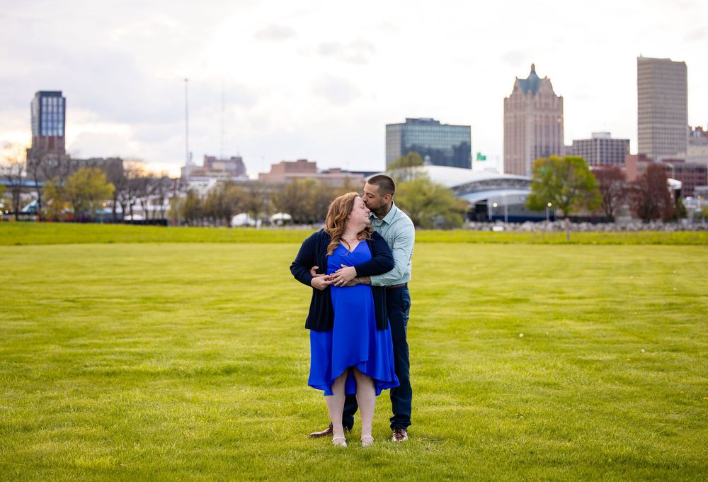 People walking and standing in a park with Boston city skyline visible in the background on a sunny day.