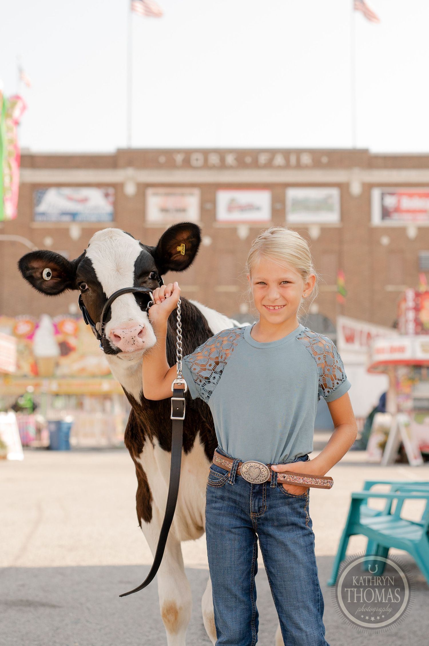 A dairy cow poses with its handler in front of the county fair entrance.