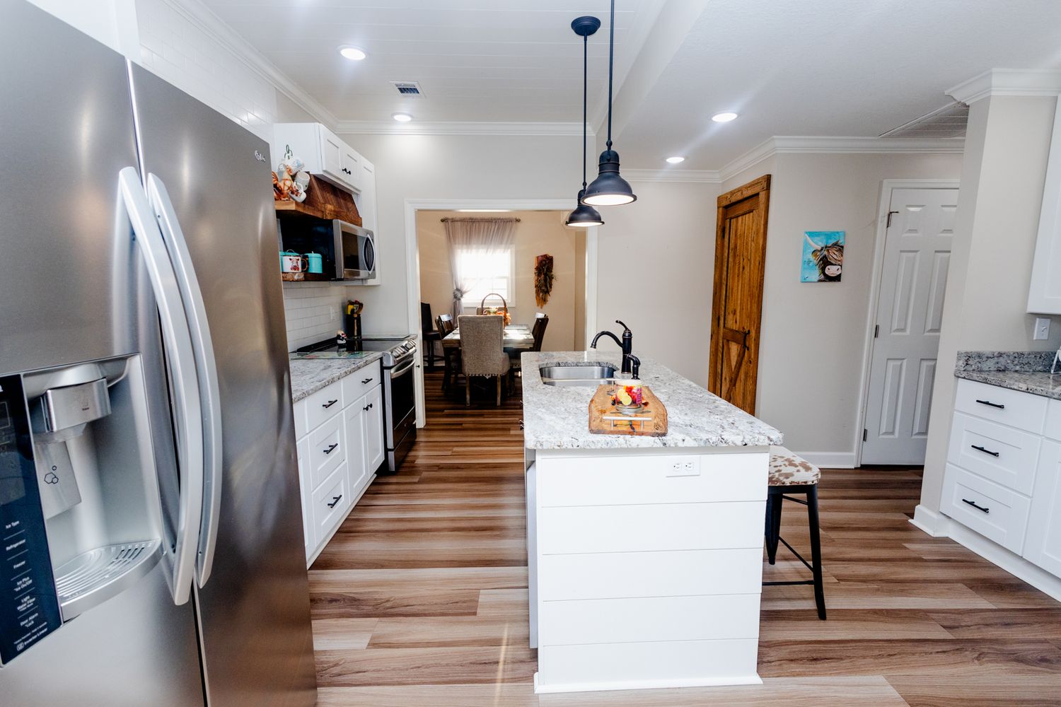 Long hallway view of modern home interior with white walls and wood floors.