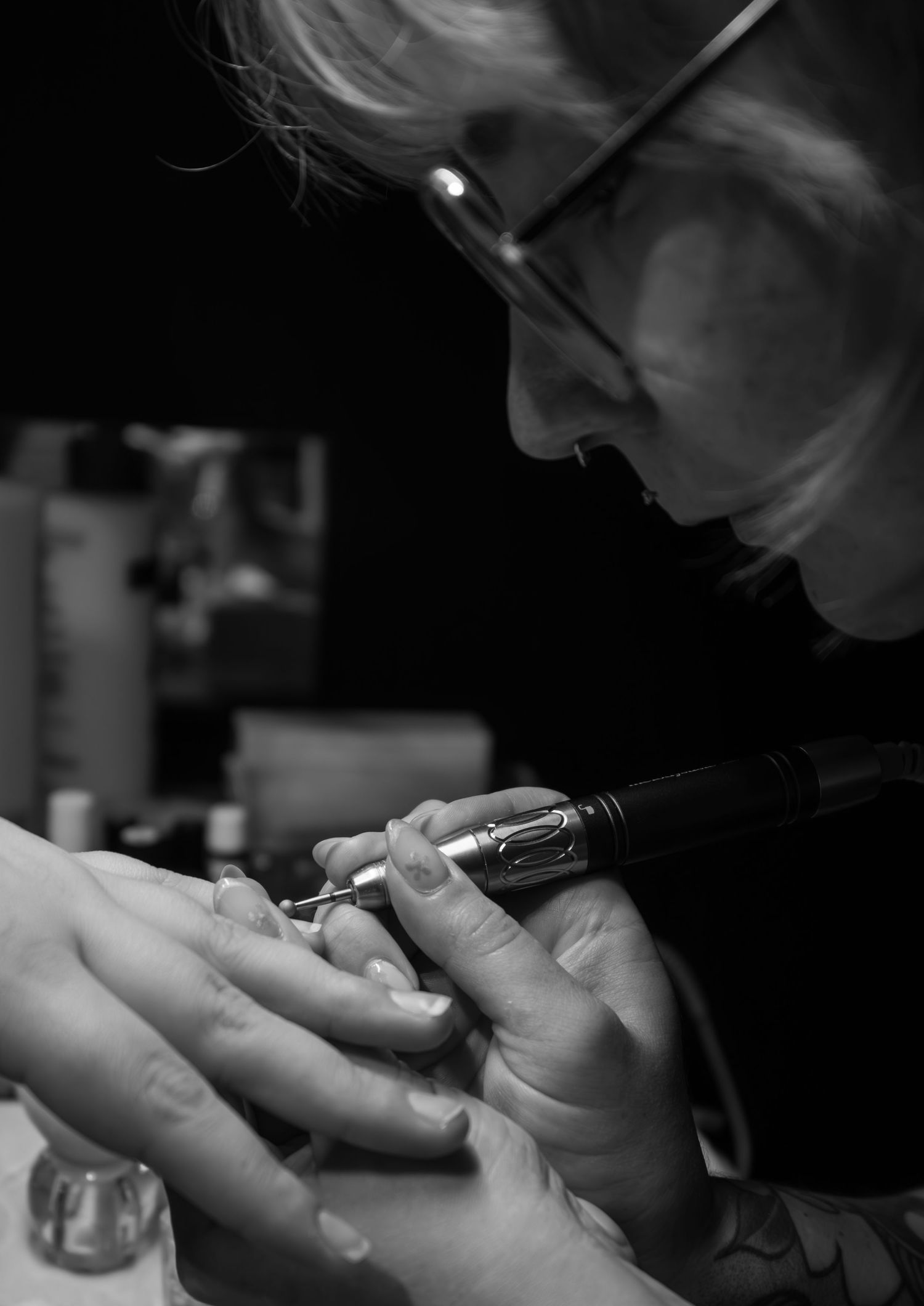 Black and white image of nail technician performing precise manicure work.