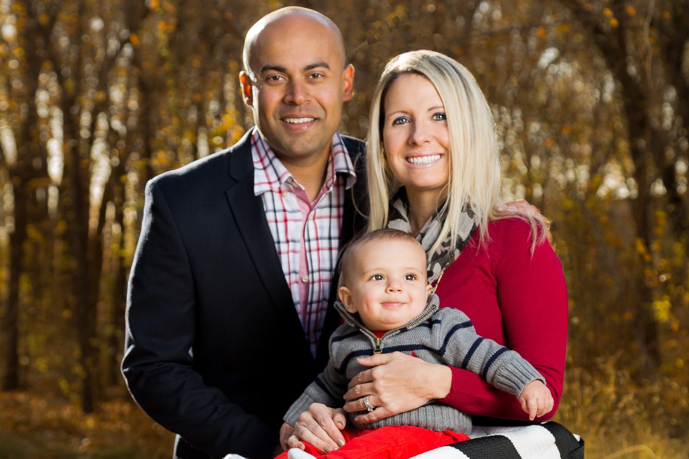 family of three with parents holding their infant son with trees in the background. Eternity Fine Portraits Vail, AZ
