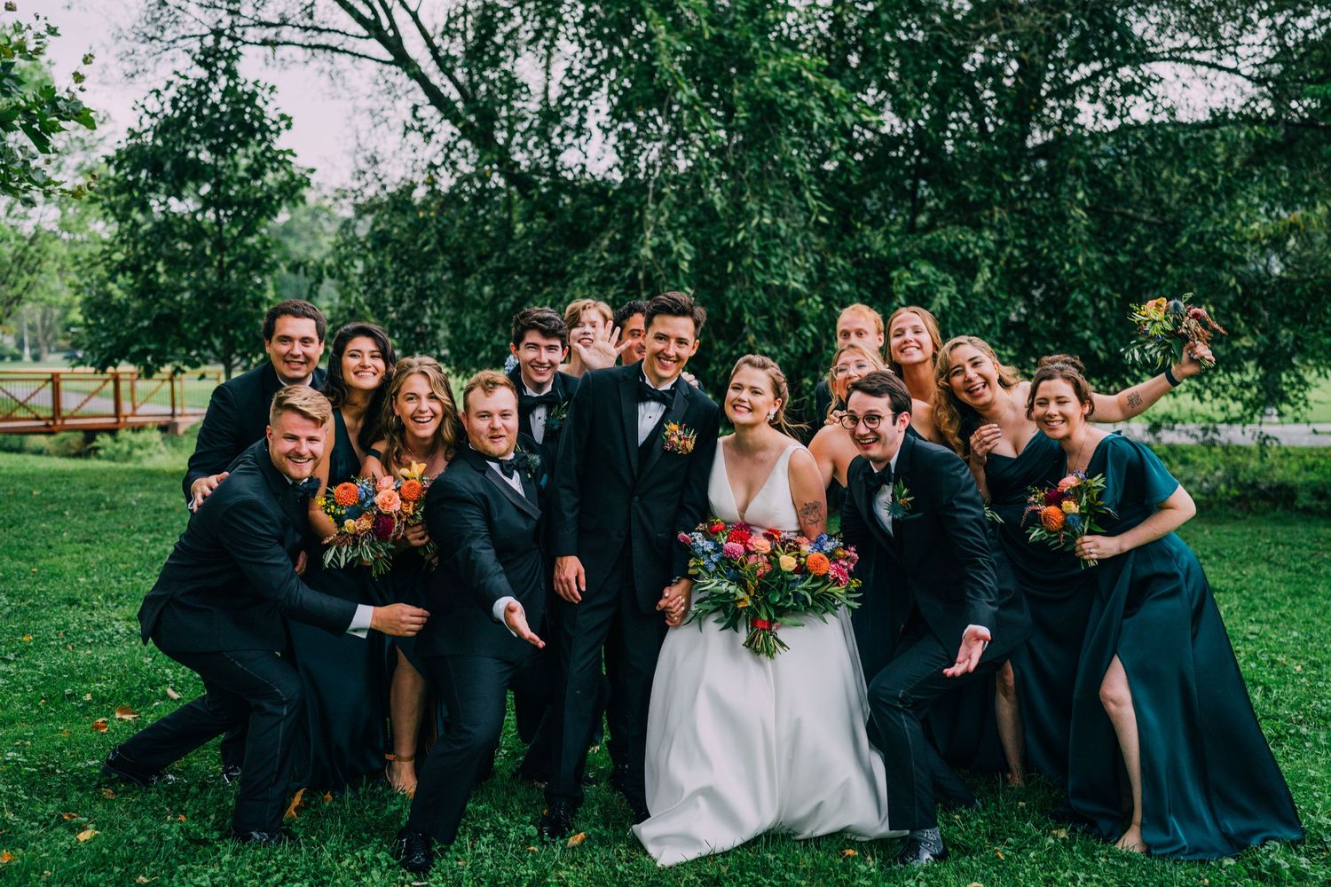 Krystyn and Nate's wedding party huddles together. They are laughing and making funny faces .
