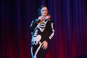 Singer performs passionately in front of a blue stage curtain during an energetic concert performance.