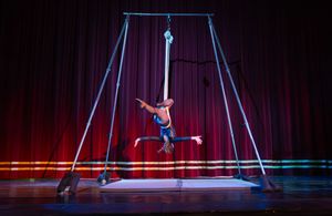 Aerial acrobat performers in dramatic silhouette perform on stage during a theatrical circus production.
