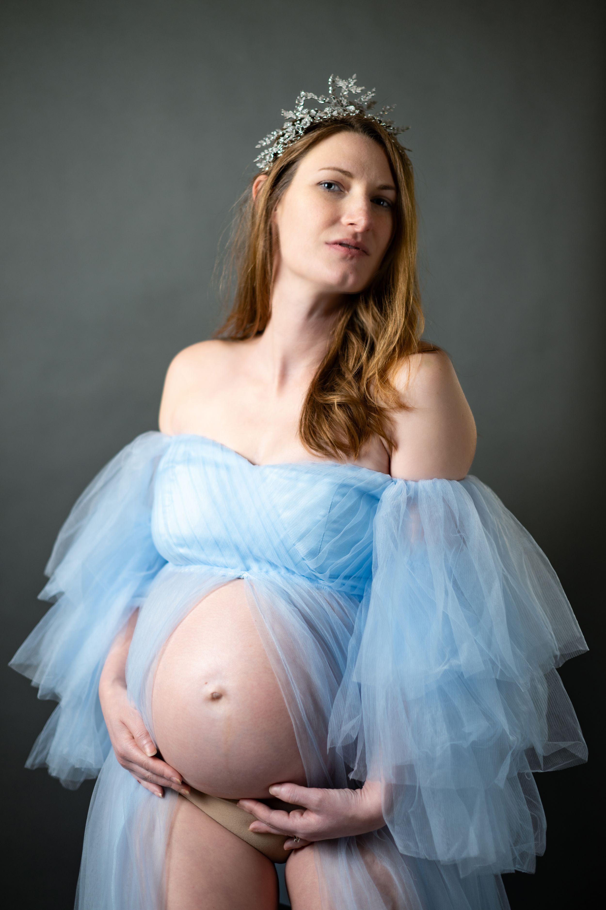 Ethereal maternity photo with crystal crown and flowing blue tulle gown.