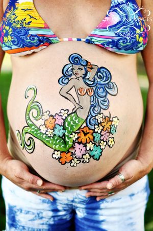 Belly art featuring colorful mermaid design painted on pregnant stomach.