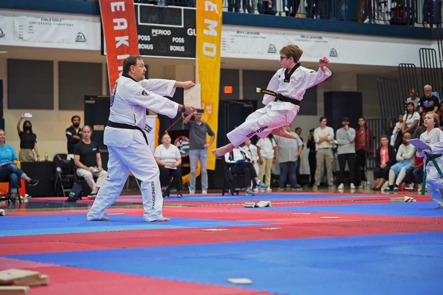 Taekwondo tournament with athletes competing on blue and red mats.