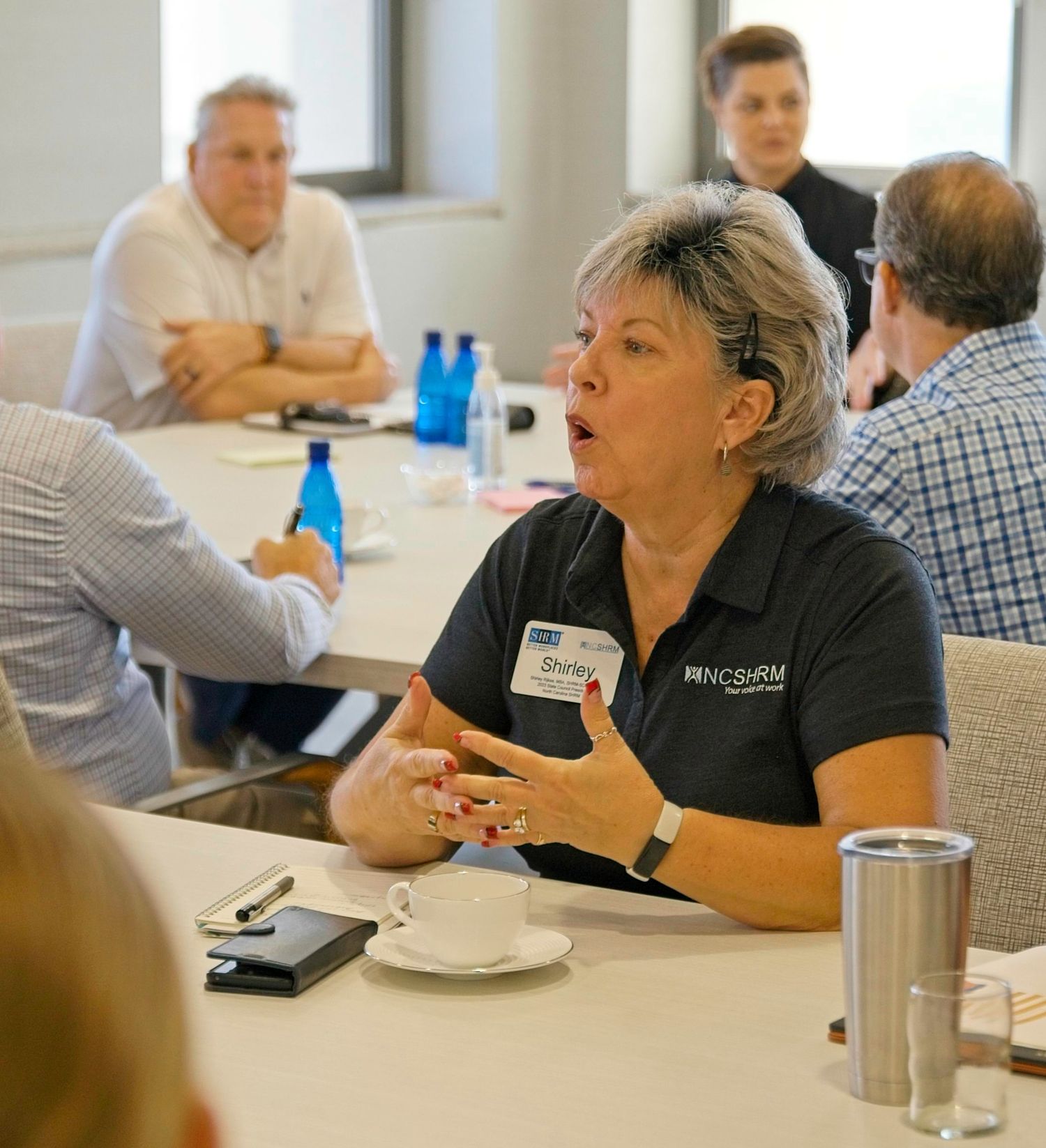 Business meeting participants engaged in discussion around a conference room table.