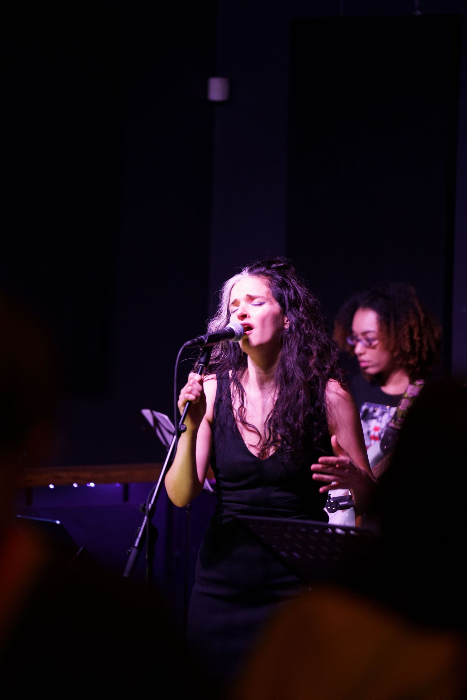 Singer performing on a dimly lit stage during a live music event.