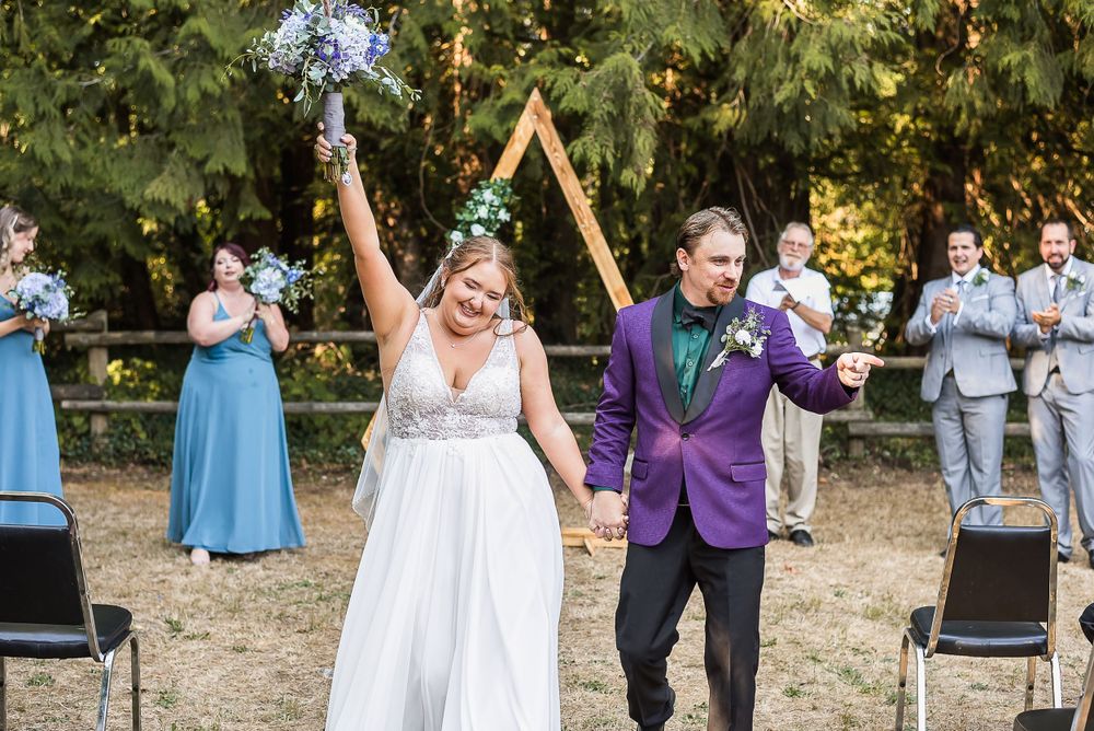 A couple celebrates that "just married" feeling by cheering as they walk down the aisle together after their ceremony.